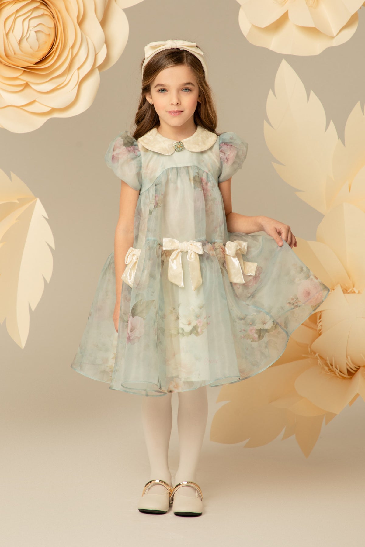 Girl wearing a pastel blue floral dress with ivory velvet bows