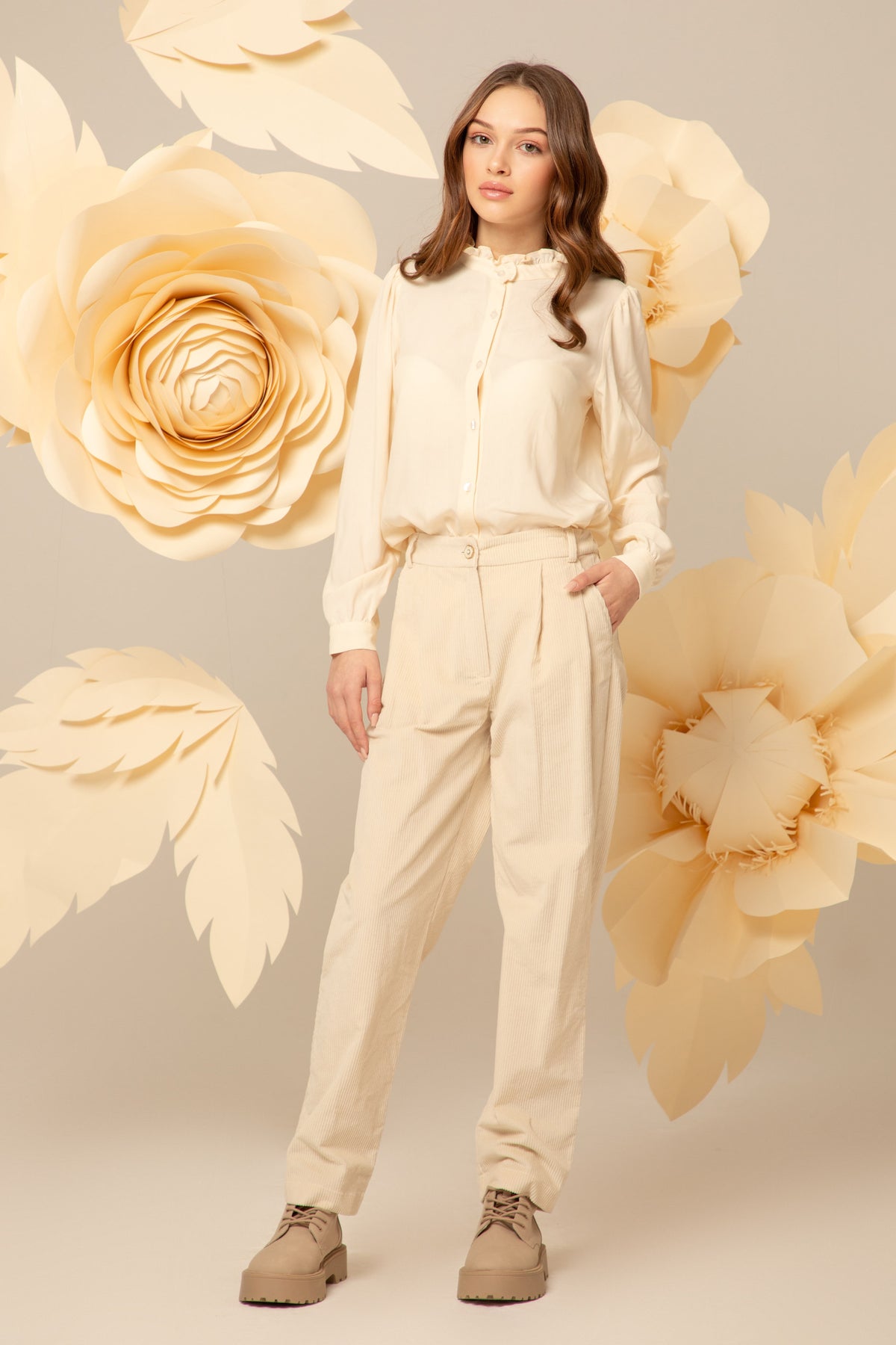 Girl wearing a cream ruffled-collar shirt with cream trousers