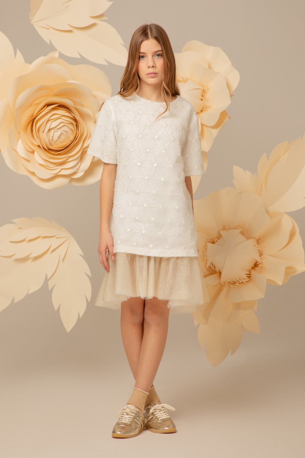 Girl wearing an ivory sequin dress with floral appliqués