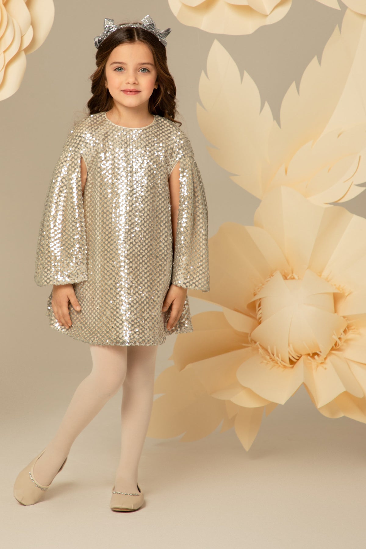 Girl wearing a silver sequin dress with cape sleeves