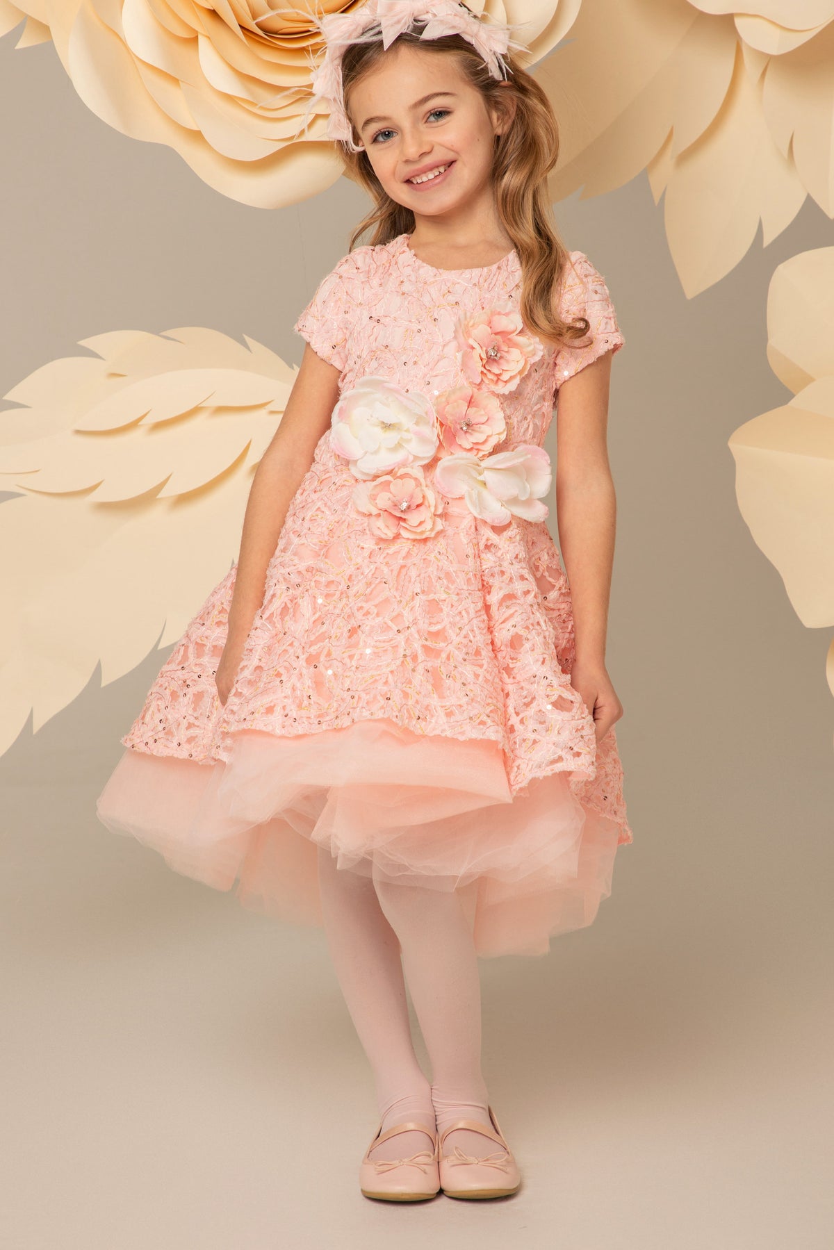 Girl wearing a pink lace dress with layered tulle skirt