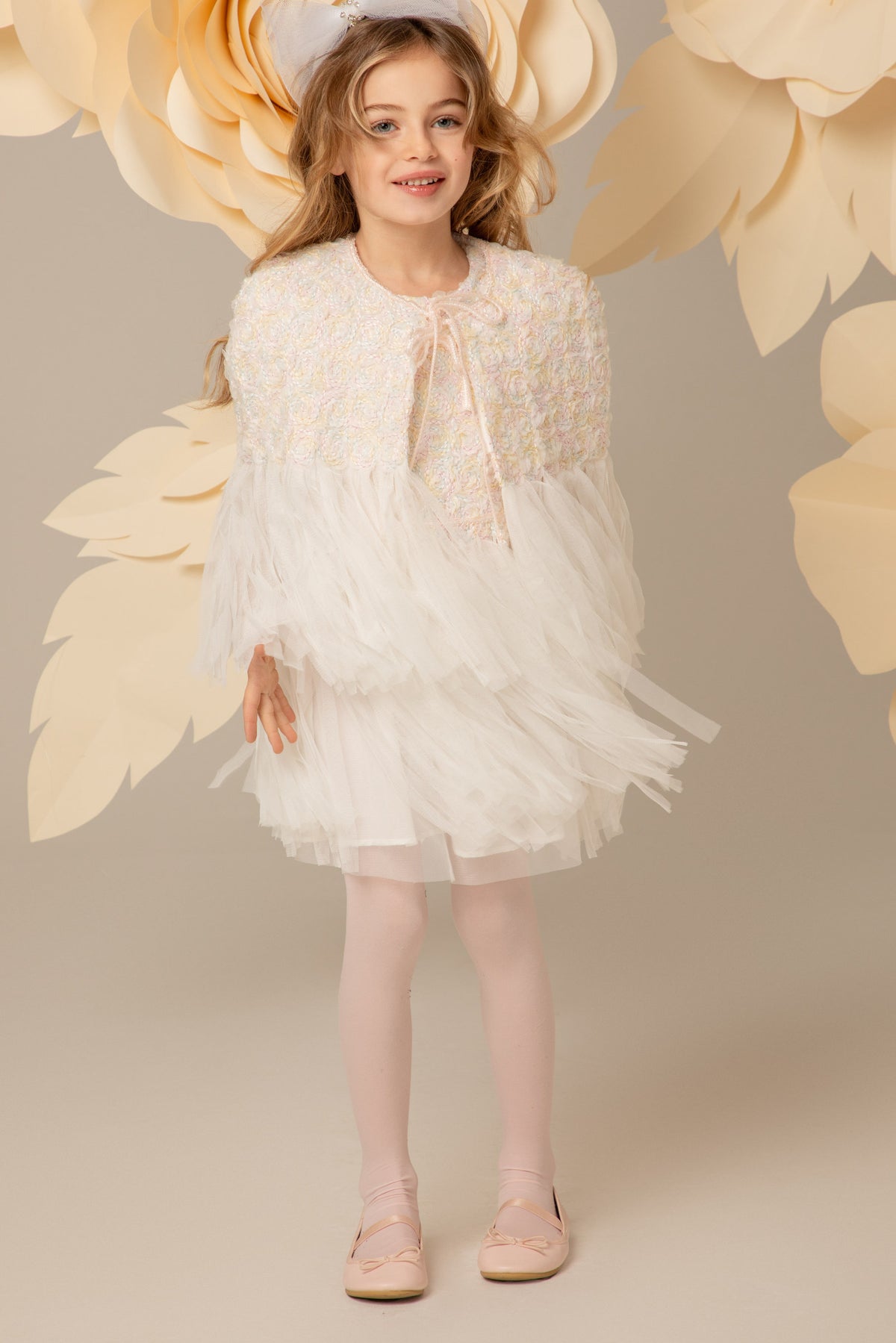 Girl wearing a white lace cape over a matching dress