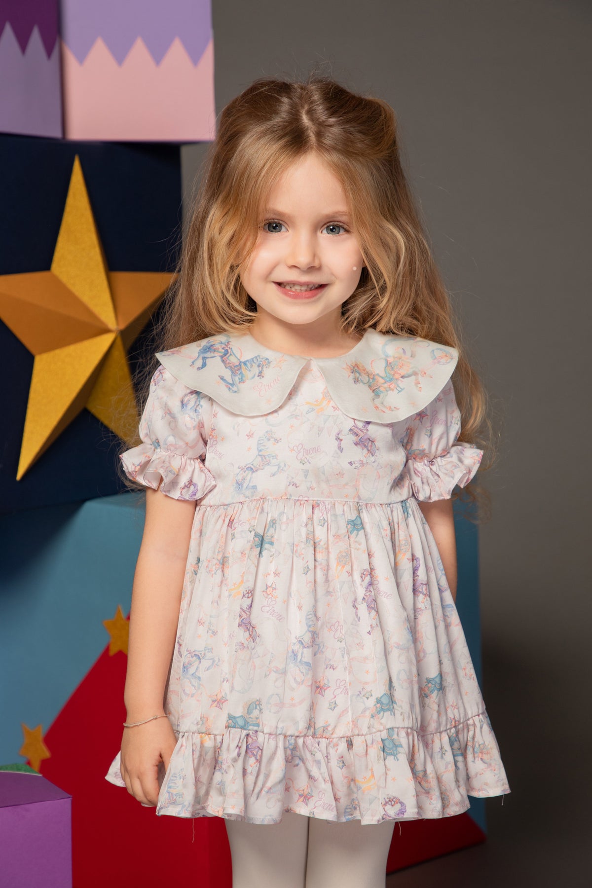 Baby girl wearing a carousel print dress with ruffle sleeves