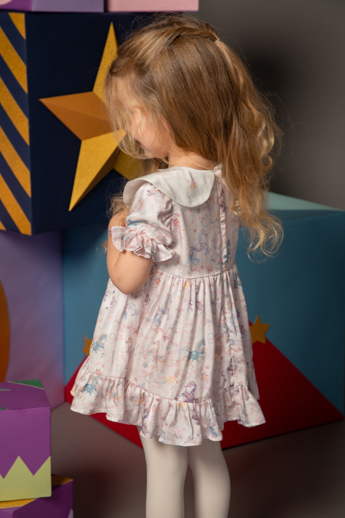 Back view of a baby dress with carousel print