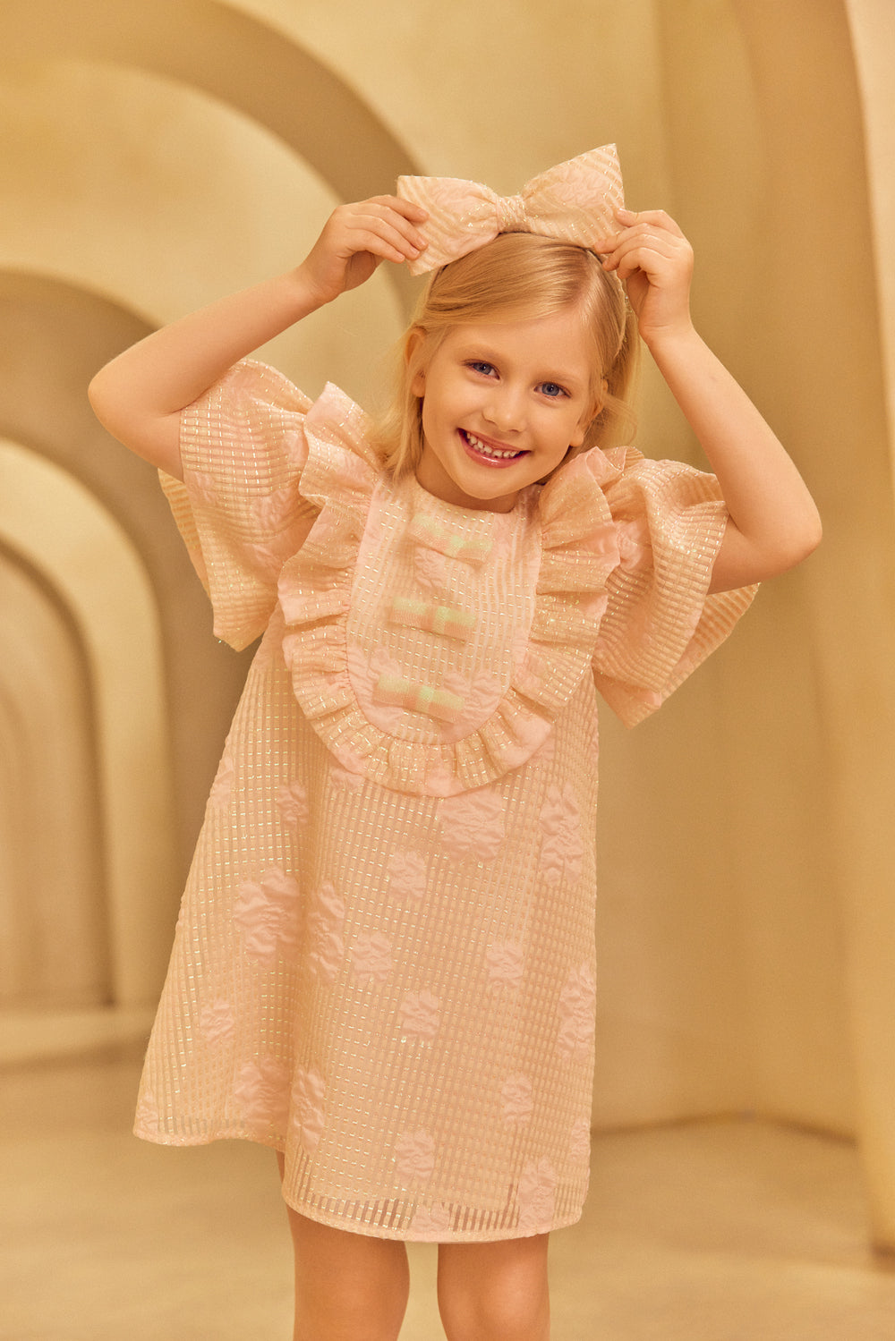 Young girl wearing a pink dress with pink headband.