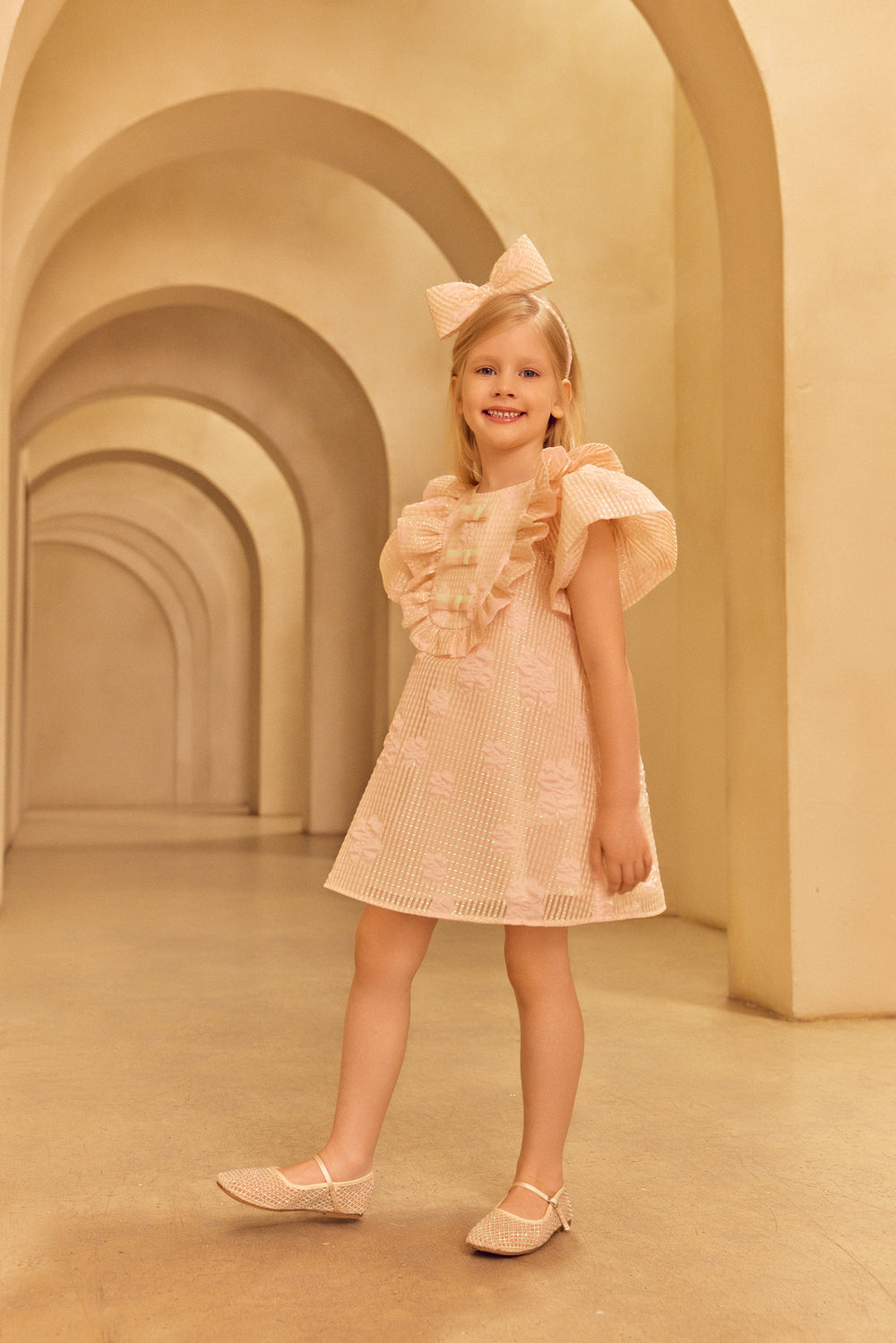 Young girl in a pink dress wearing a pink headband.