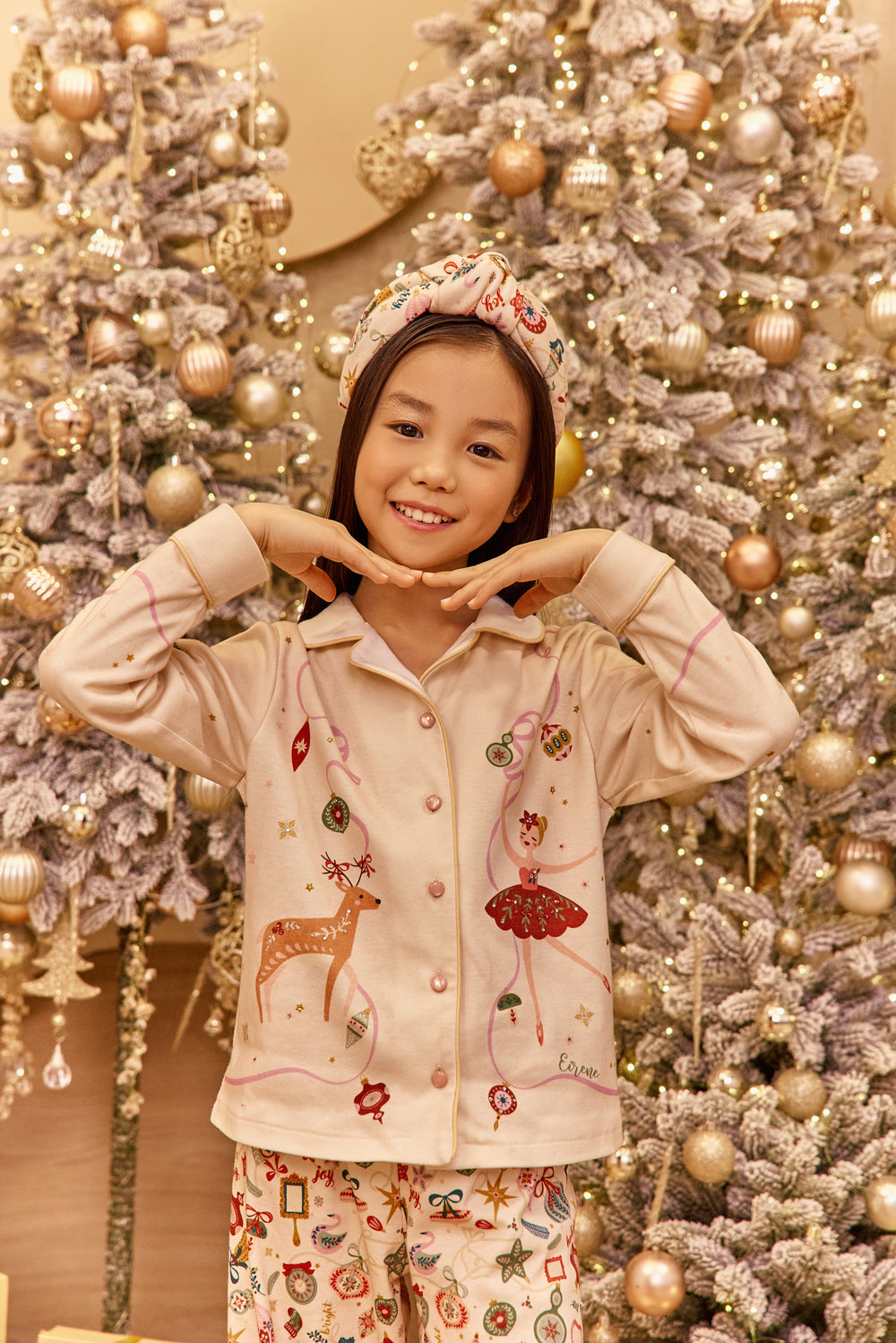 Child in pajamas posing in front of a decorated Christmas tree