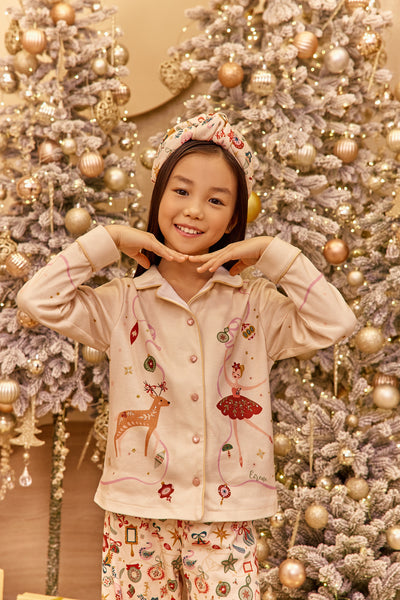 Child in pajamas posing in front of a decorated Christmas tree