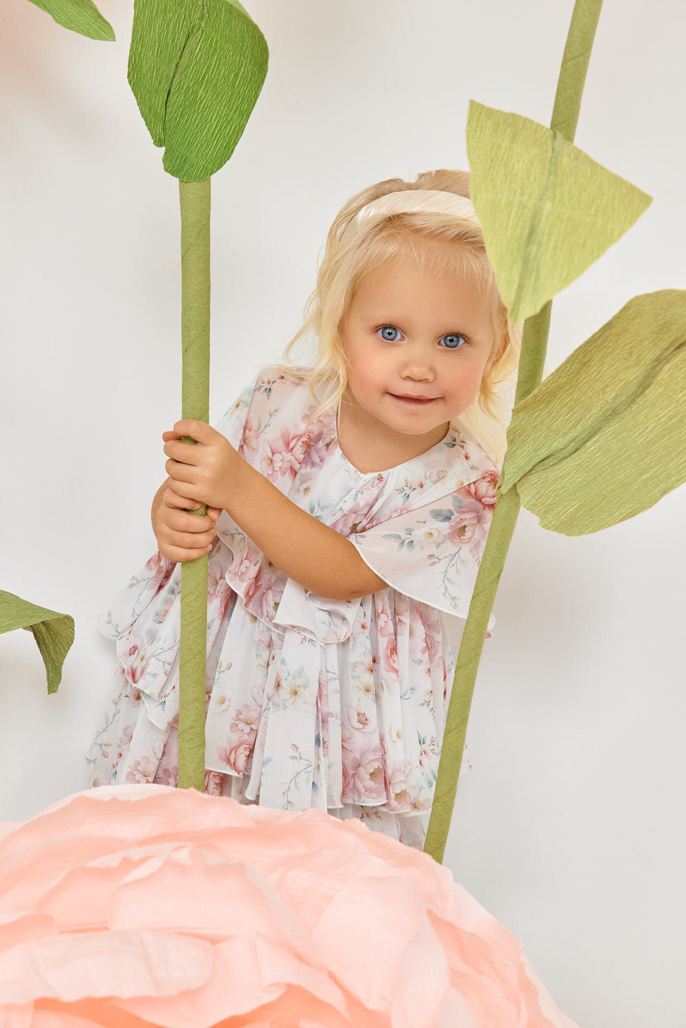 فستان أطفال أبيض مزين بكشكشة من الشيفون الزهري مع فيونكة، مع سروال داخلي مطابق.