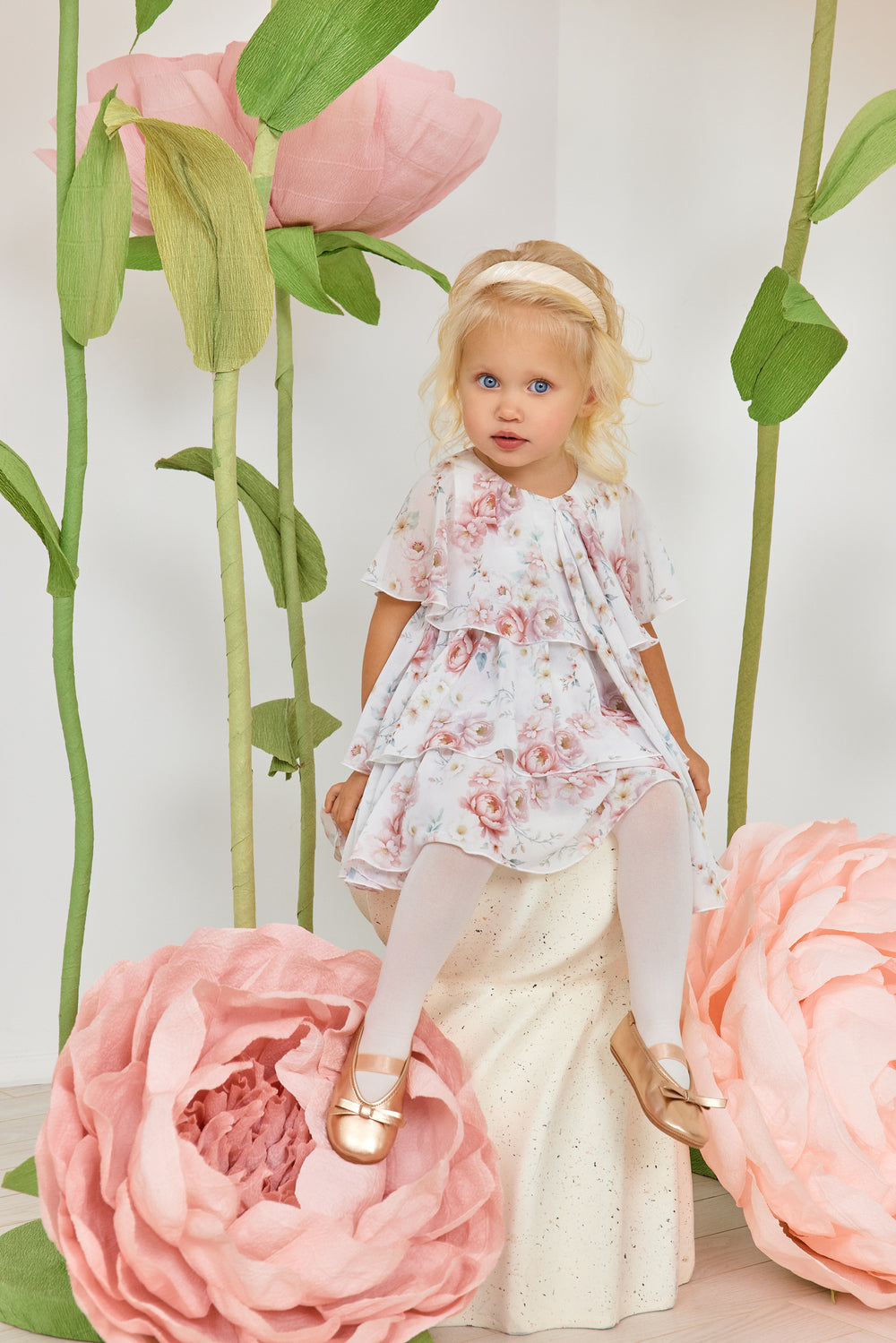 فستان أطفال أبيض مزين بكشكشة من الشيفون الزهري مع فيونكة، مع سروال داخلي مطابق.