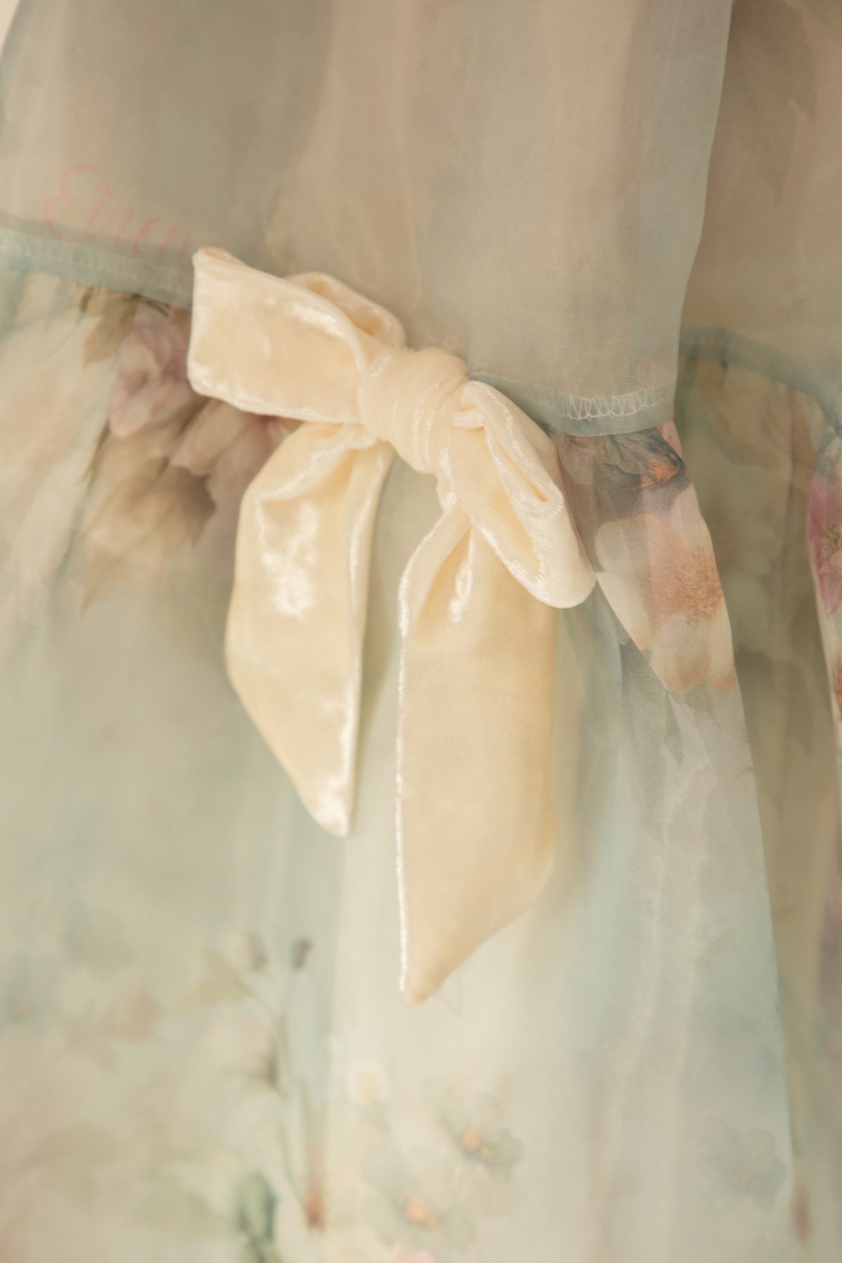 Close-up of the ivory velvet bow on a pastel blue dress
