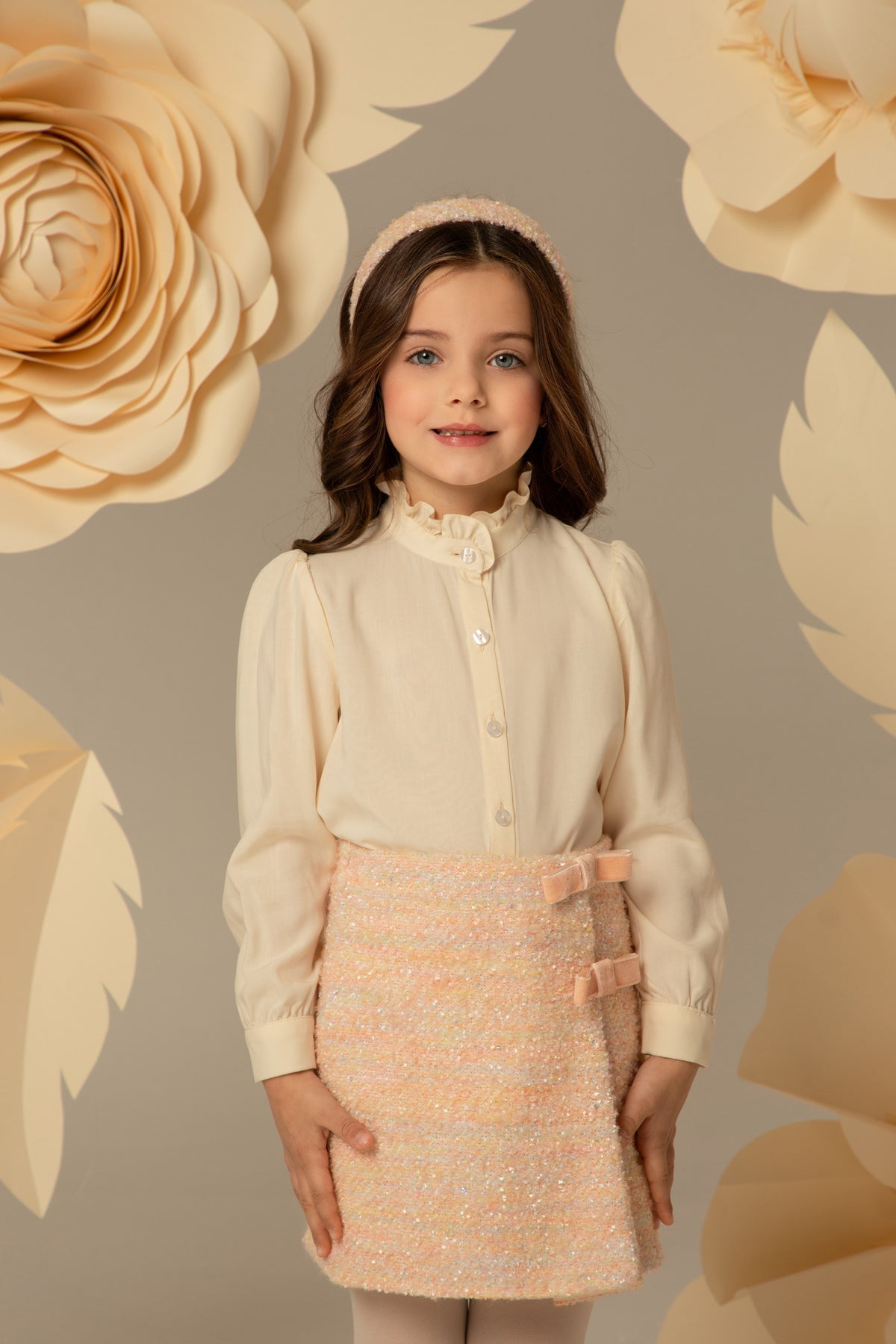 Cream shirt with a ruffled collar worn with a pink tweed skirt