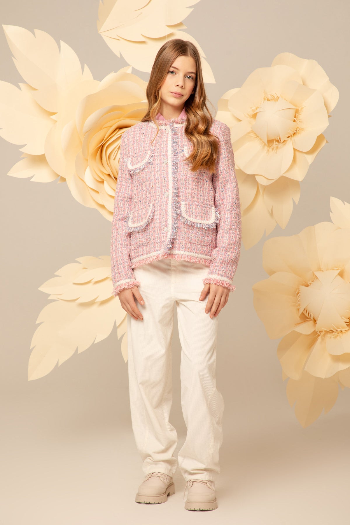 Girl wearing a pink and white tweed blazer with gold buttons