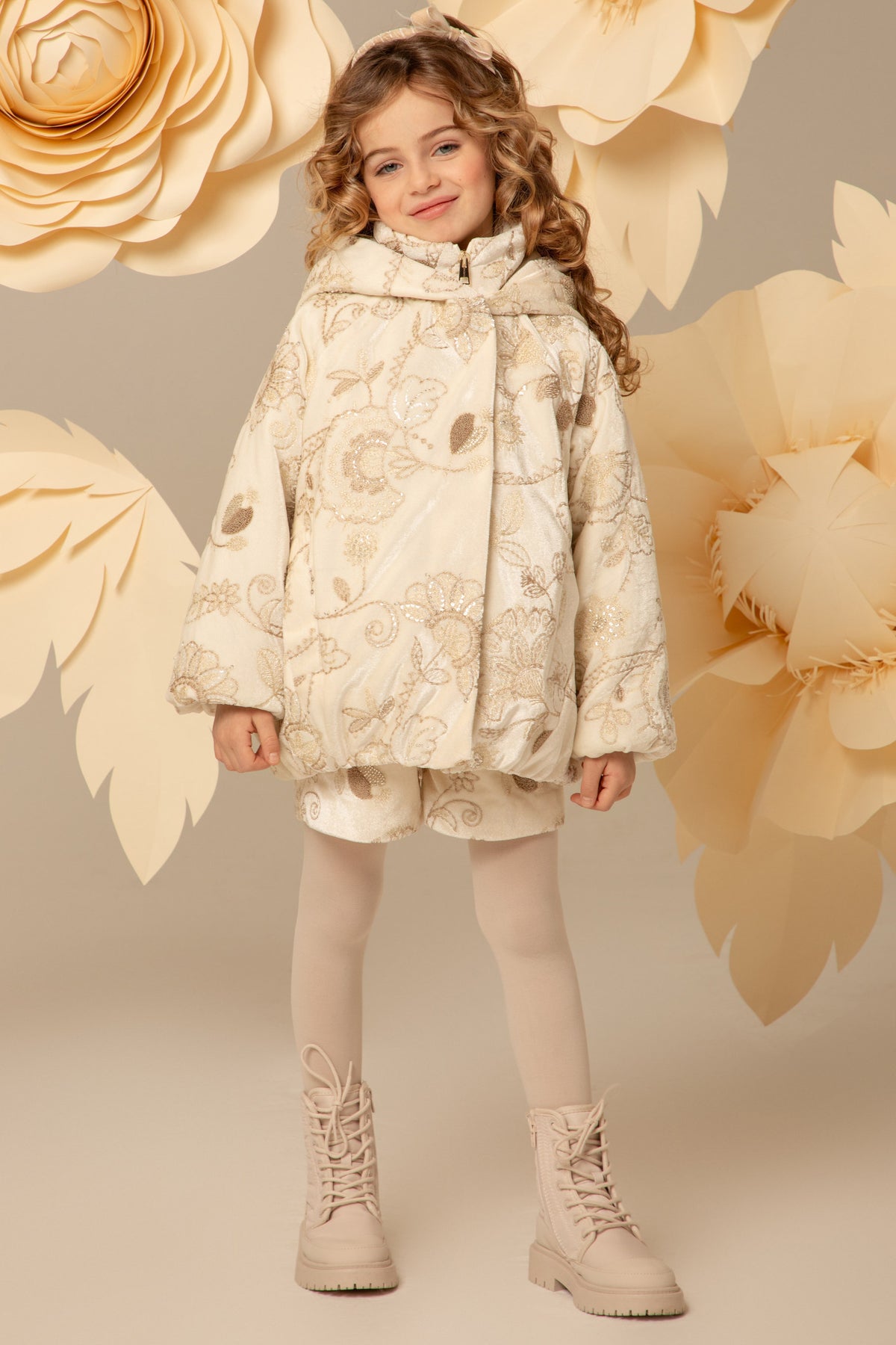 Girl wearing an ivory velvet padded coat with gold embroidery