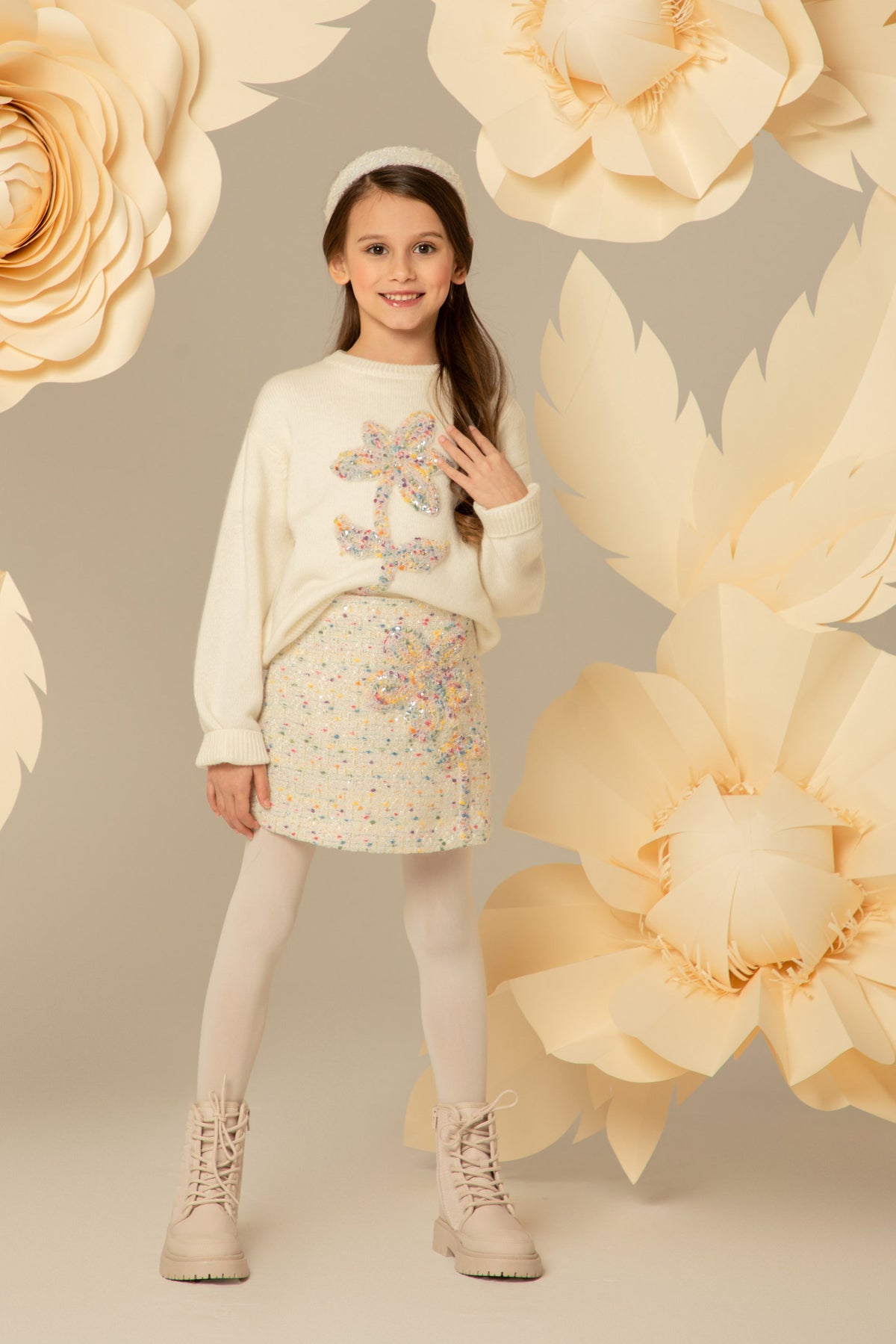 Girl wearing a cream tweed skirt with a floral appliqué