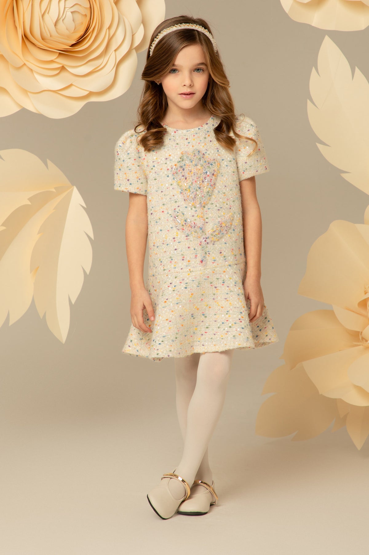 Girl wearing a cream tweed dress with puff sleeves