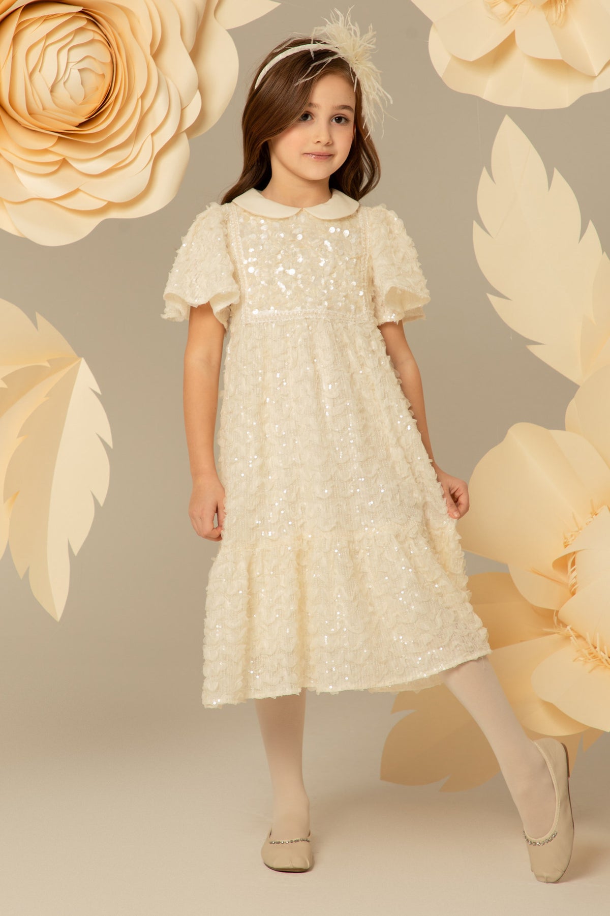 Girl wearing an ivory sequinned midi dress with a Peter Pan collar