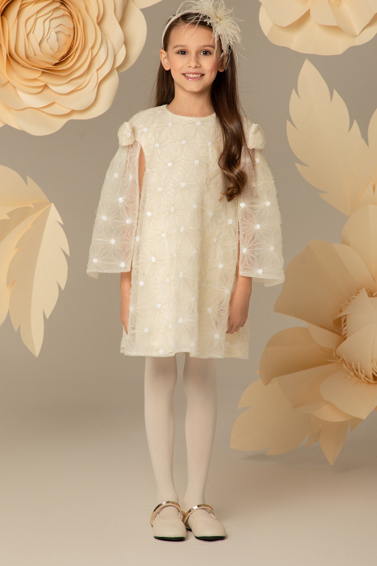 Girl wearing an ivory A-line lace dress with cape sleeves