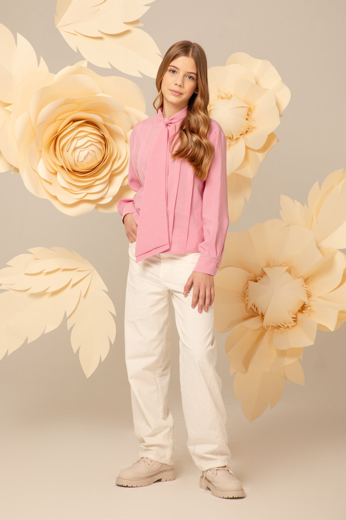 Girl wearing a soft pink blouse with a tie neck