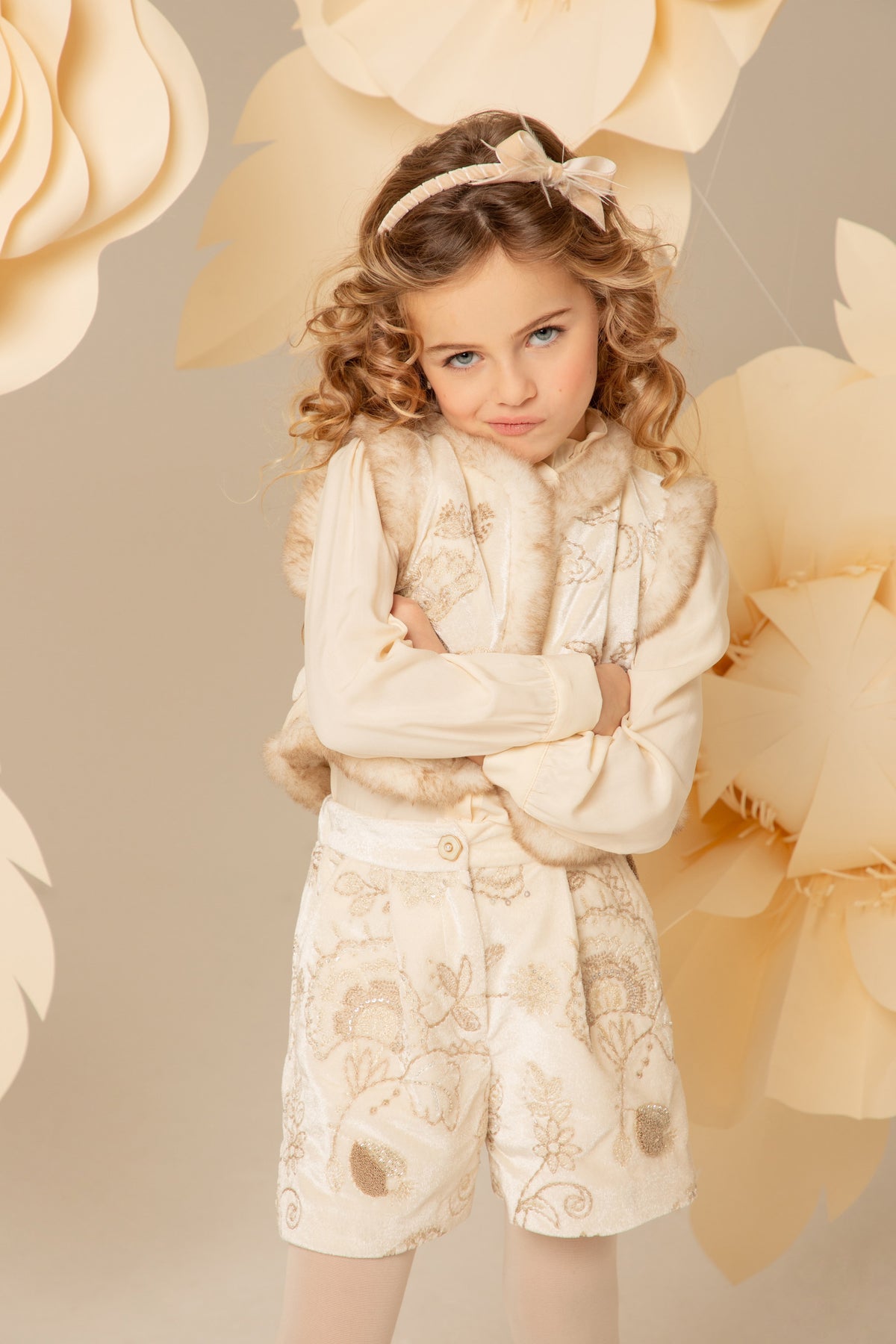 Girl wearing an ivory velvet padded vest with gold embroidery