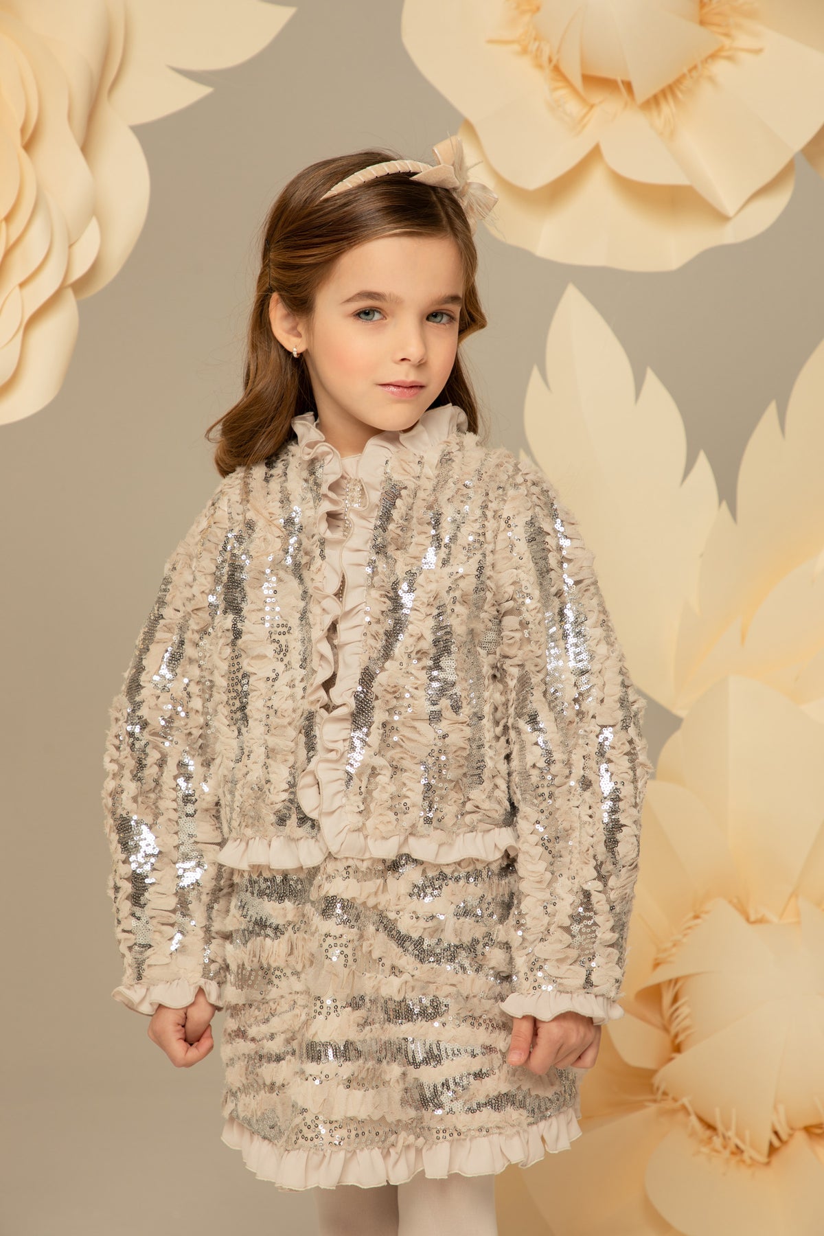 Girl wearing a nude sequin blazer with ruffle trim