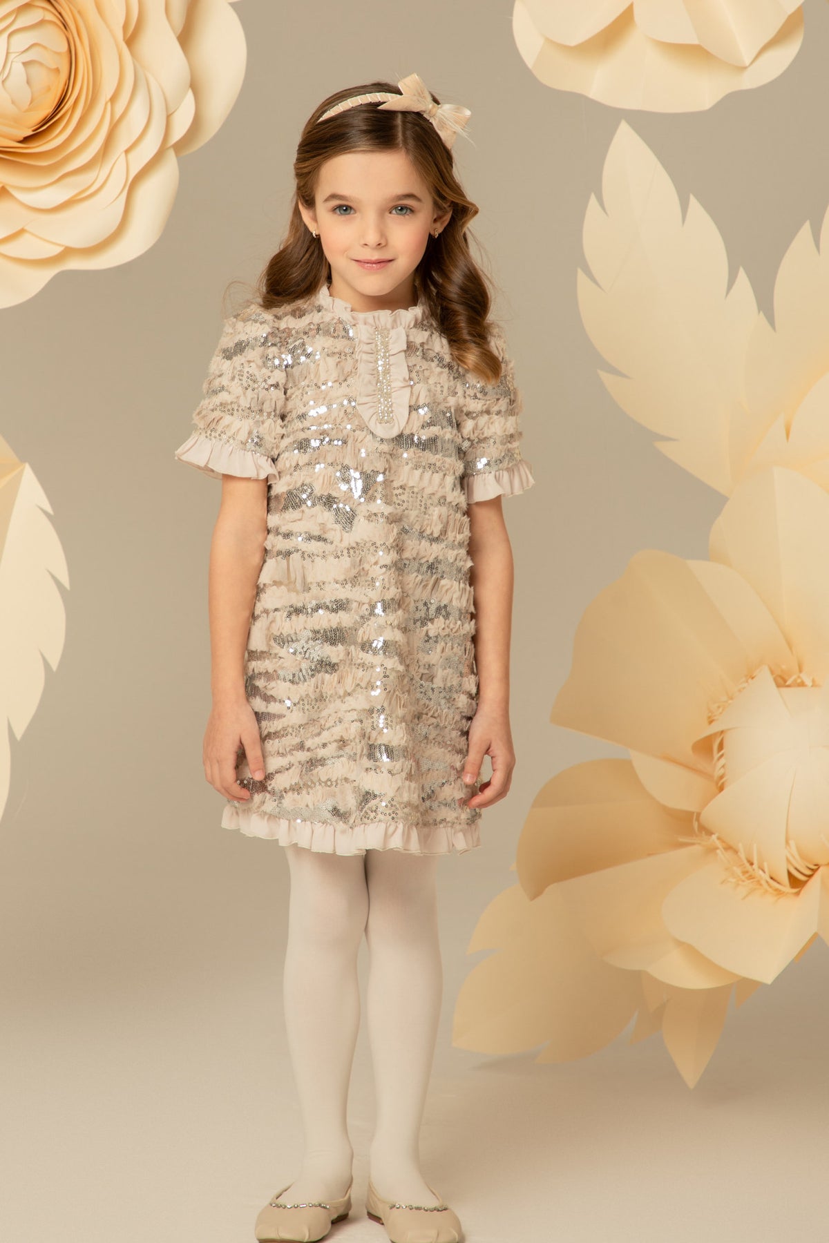Girl wearing a beige A-line dress with silver sequins