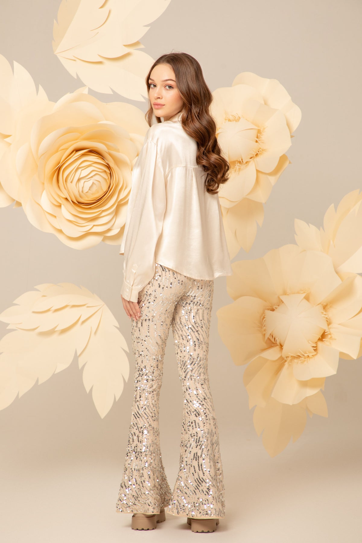 Girl wearing beige flared trousers covered in silver sequins