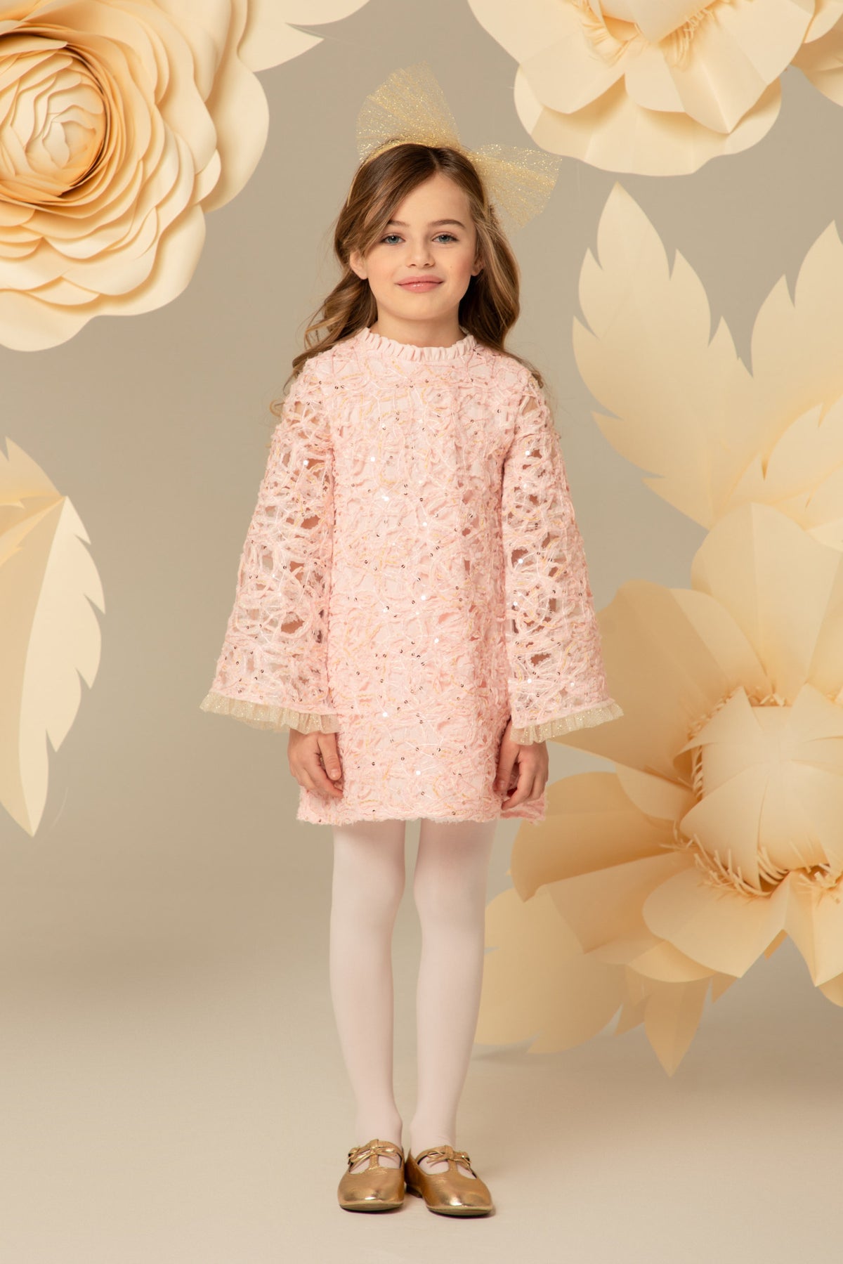 Girl wearing a pink lace A-line dress with flared sleeves