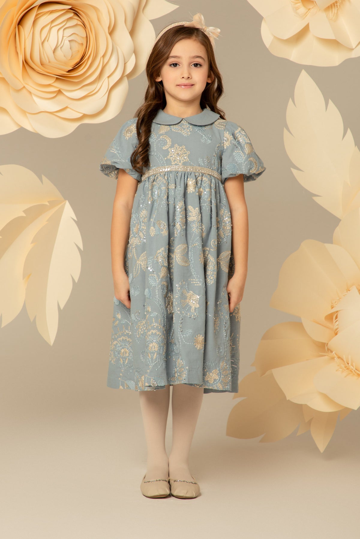 Girl wearing a powder blue dress with gold floral embroidery