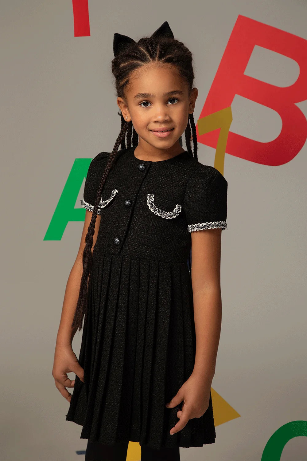 Black tweed dress with short sleeves, pleated skirt and decorative pockets with white trim