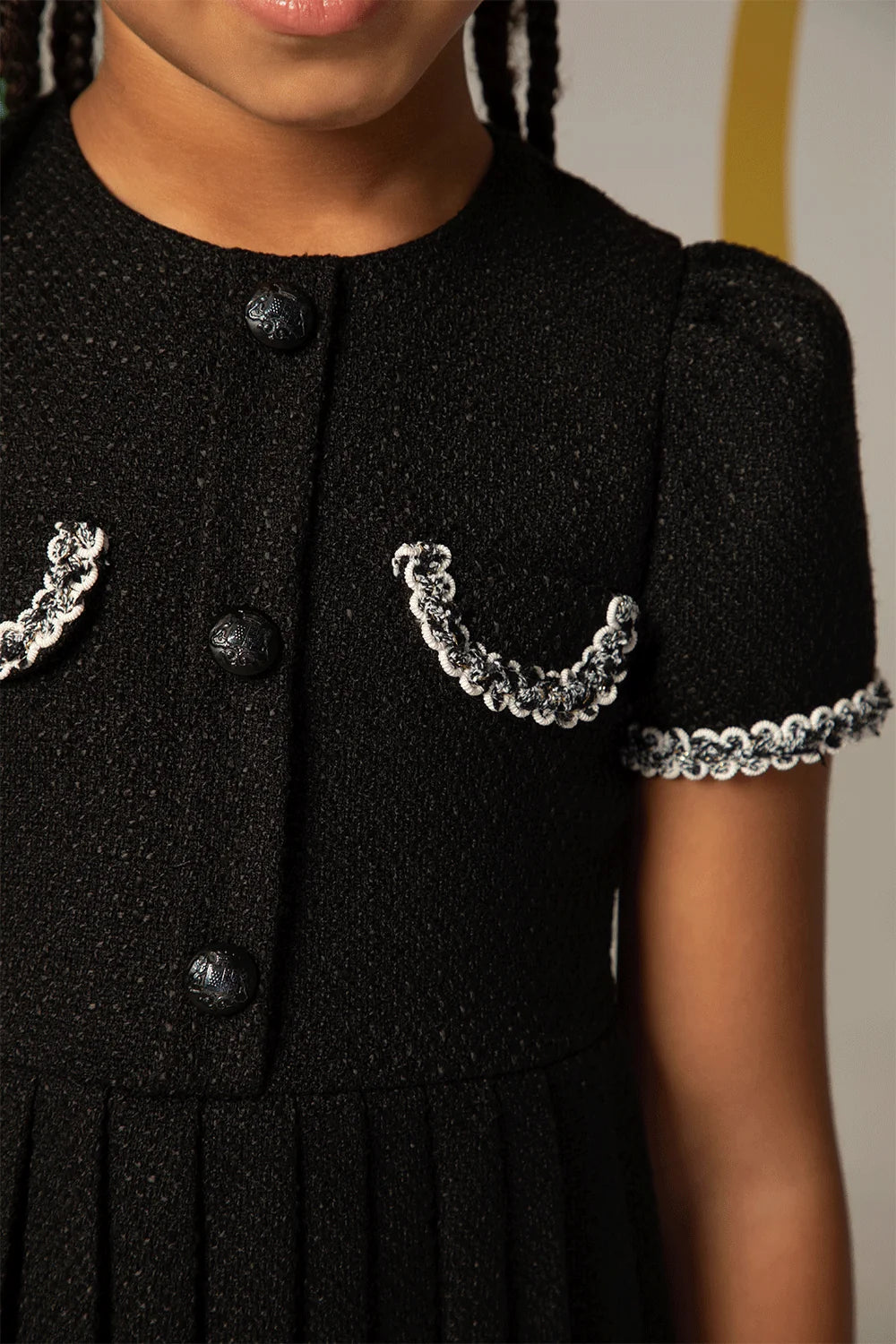 Black tweed dress with short sleeves, pleated skirt and decorative pockets with white trim