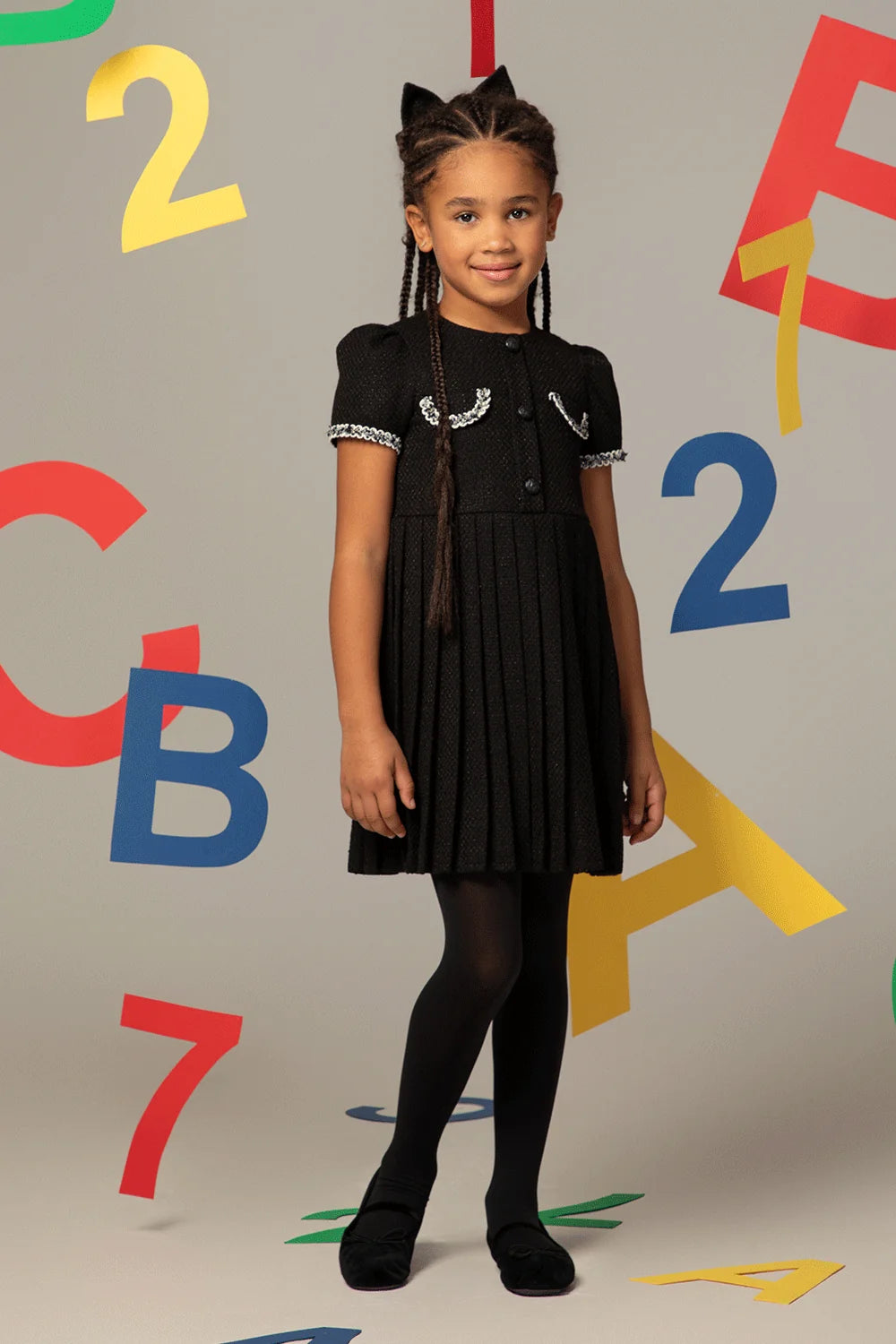 Black tweed dress with short sleeves, pleated skirt and decorative pockets with white trim
