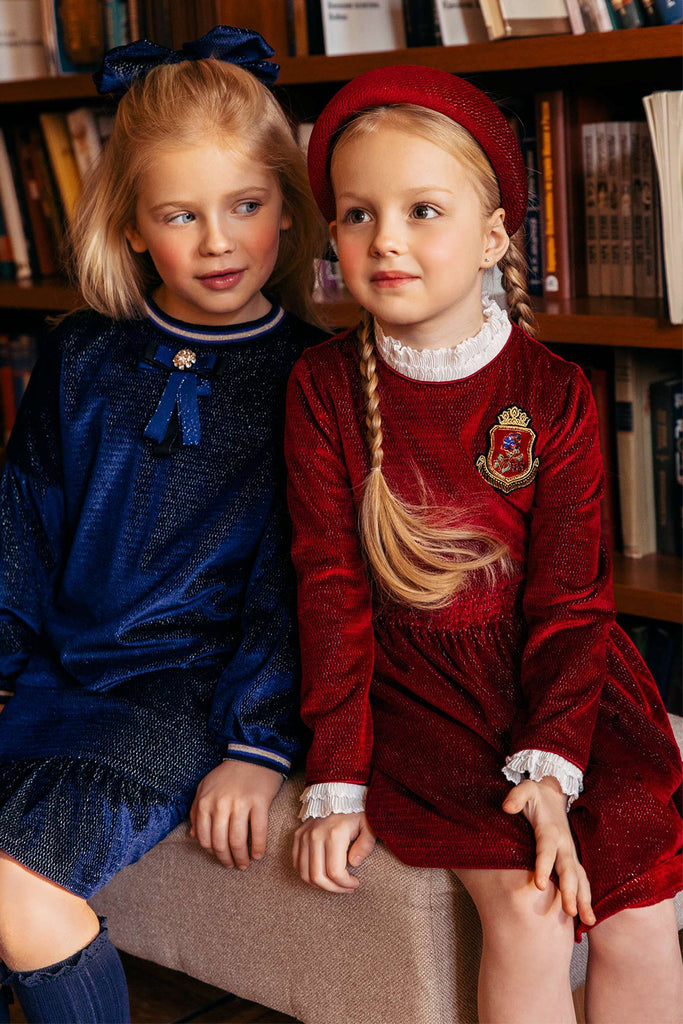 Red shimmering velvet dress with white collar and cuffs and emroidered patch
