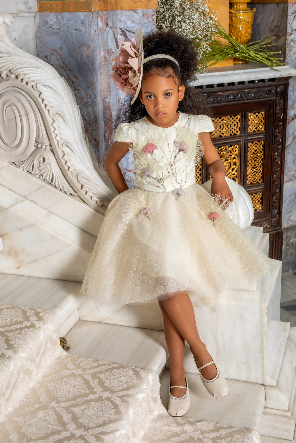 Young girl in a white floral dress sitting on a marble staircase.