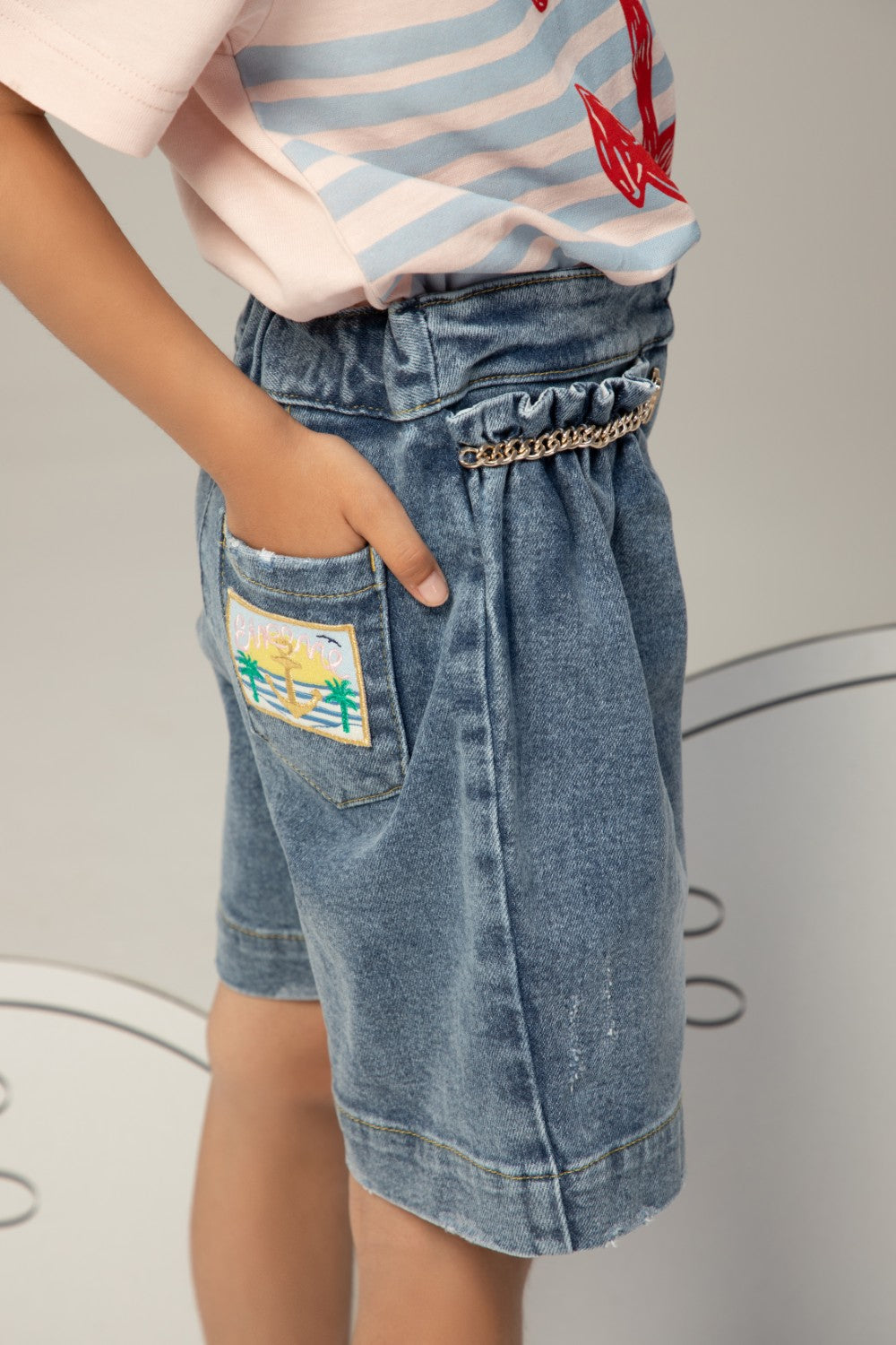 High-waisted denim shorts with a ruffled waistband, heart charm chain, and a relaxed, wide-leg fit