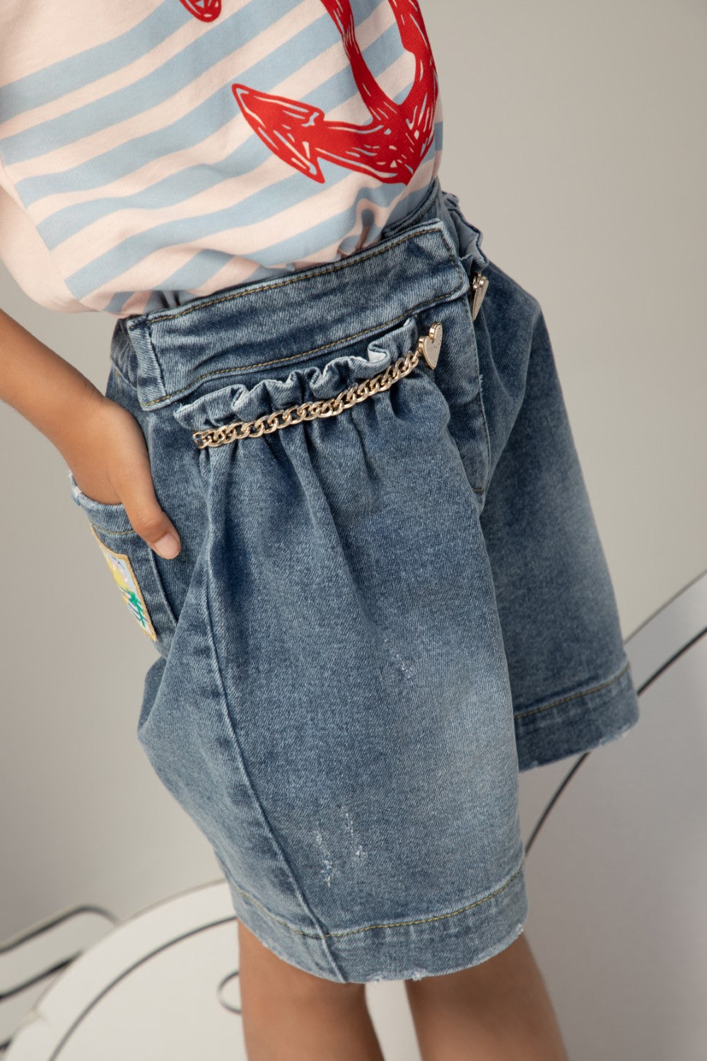 High-waisted denim shorts with a ruffled waistband, heart charm chain, and a relaxed, wide-leg fit