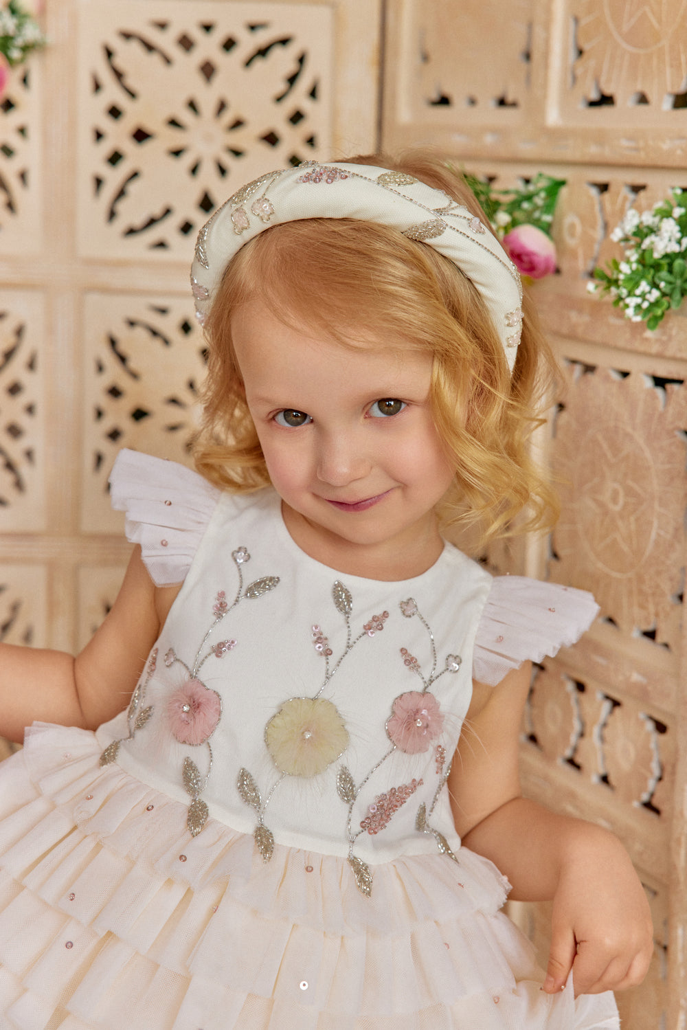 Young girl in a floral ivory dress with angel wings.