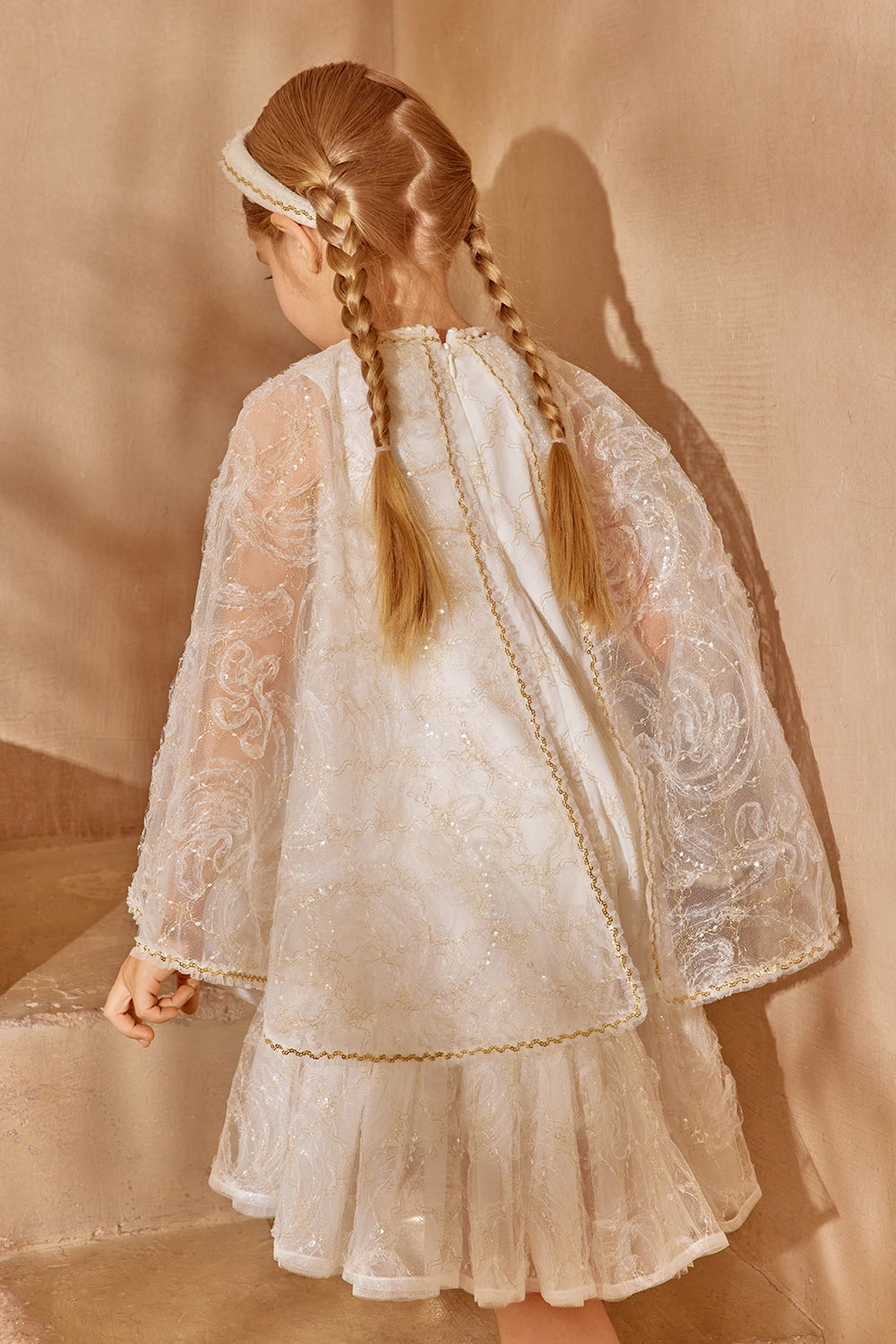 فستان من الدانتيل العاجي والذهبي بأكمام واسعة شفافة تشبه الكاب