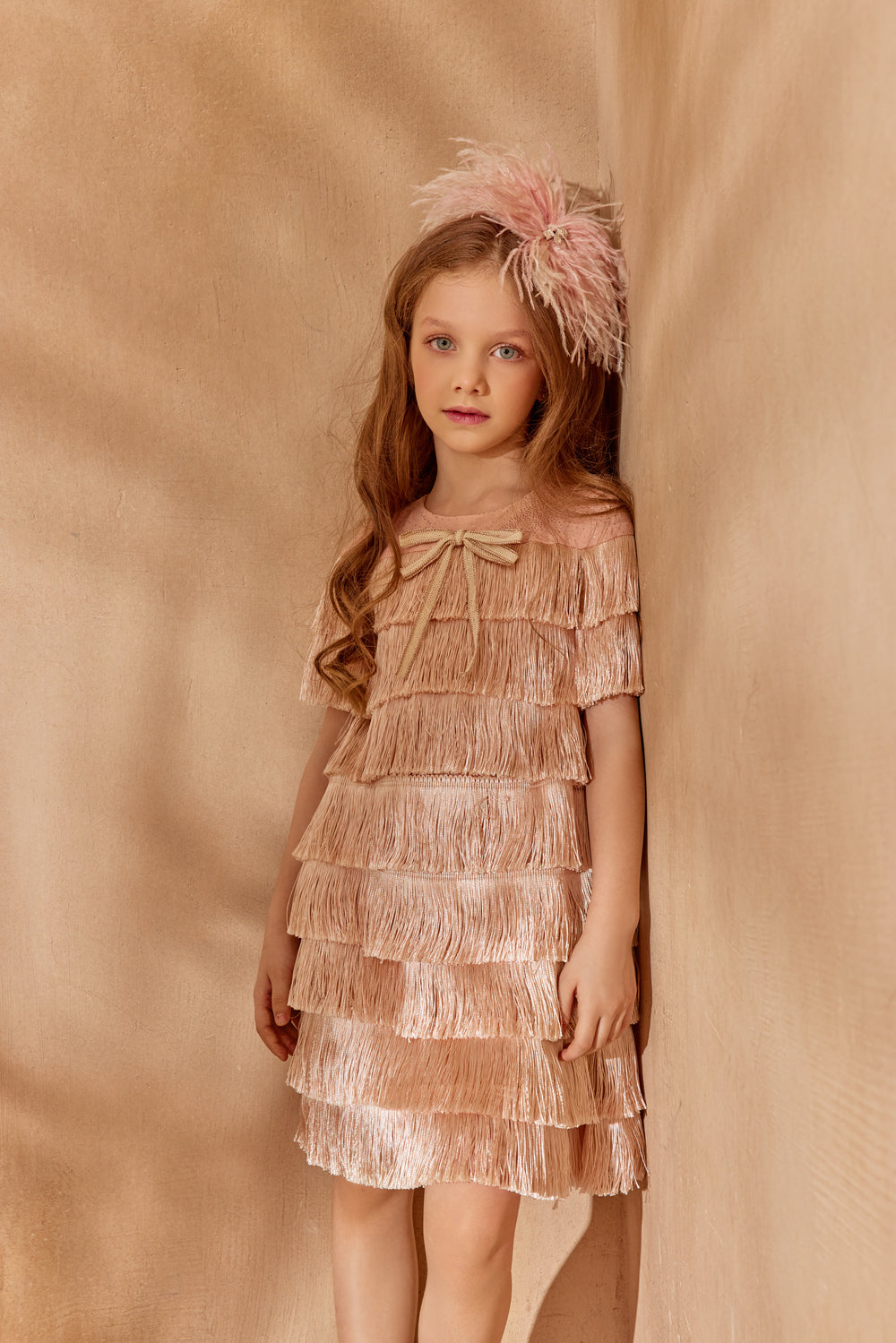 Young girl in a layered dress with a bow and floral headband.