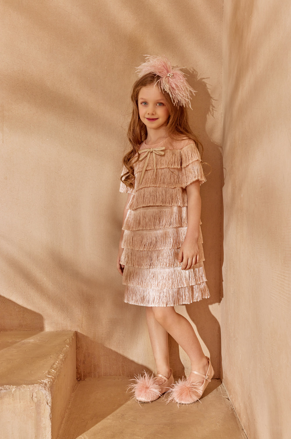 Young girl in a metallic dress with feathered headband and shoes.