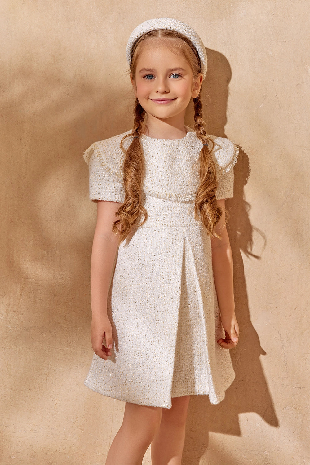 فستان أبيض أنيق من التويد ذو ثنيات أمامية وحواف مزينة بشراشيب