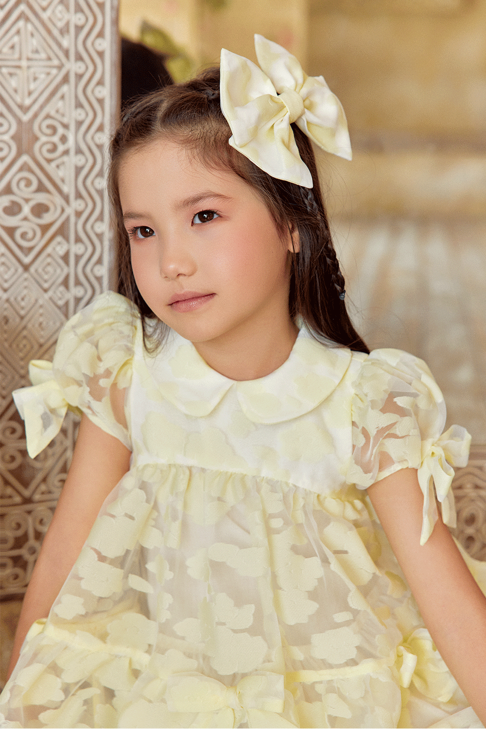 Pale yellow organza dress with texture, puff sleeves, and bows