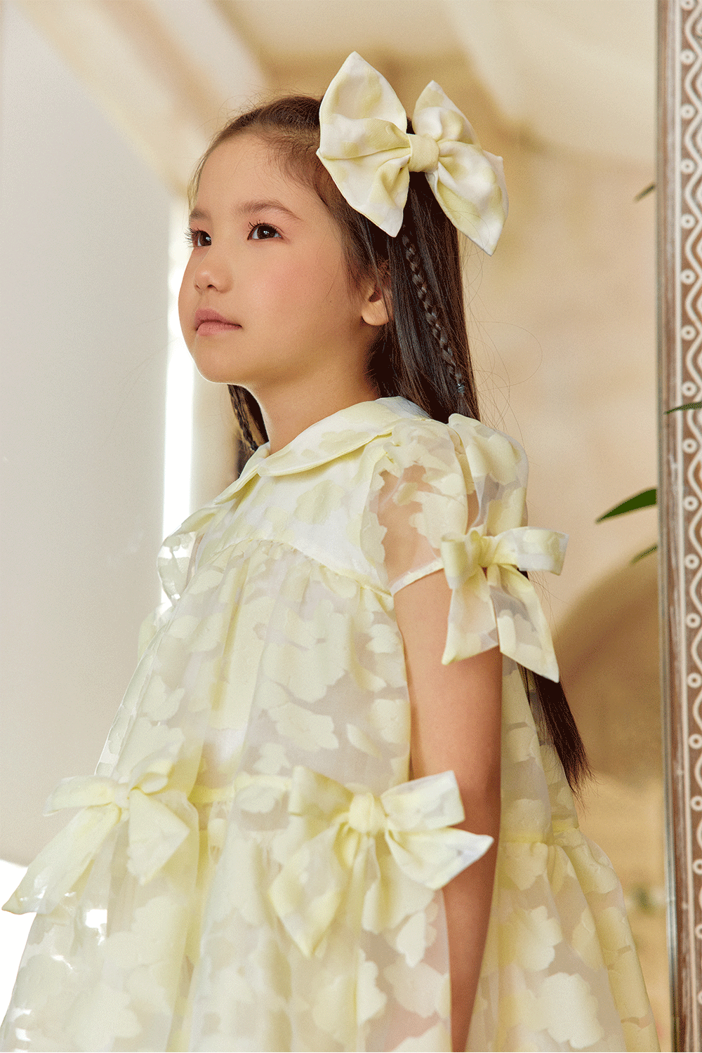 Pale yellow organza dress with texture, puff sleeves, and bows