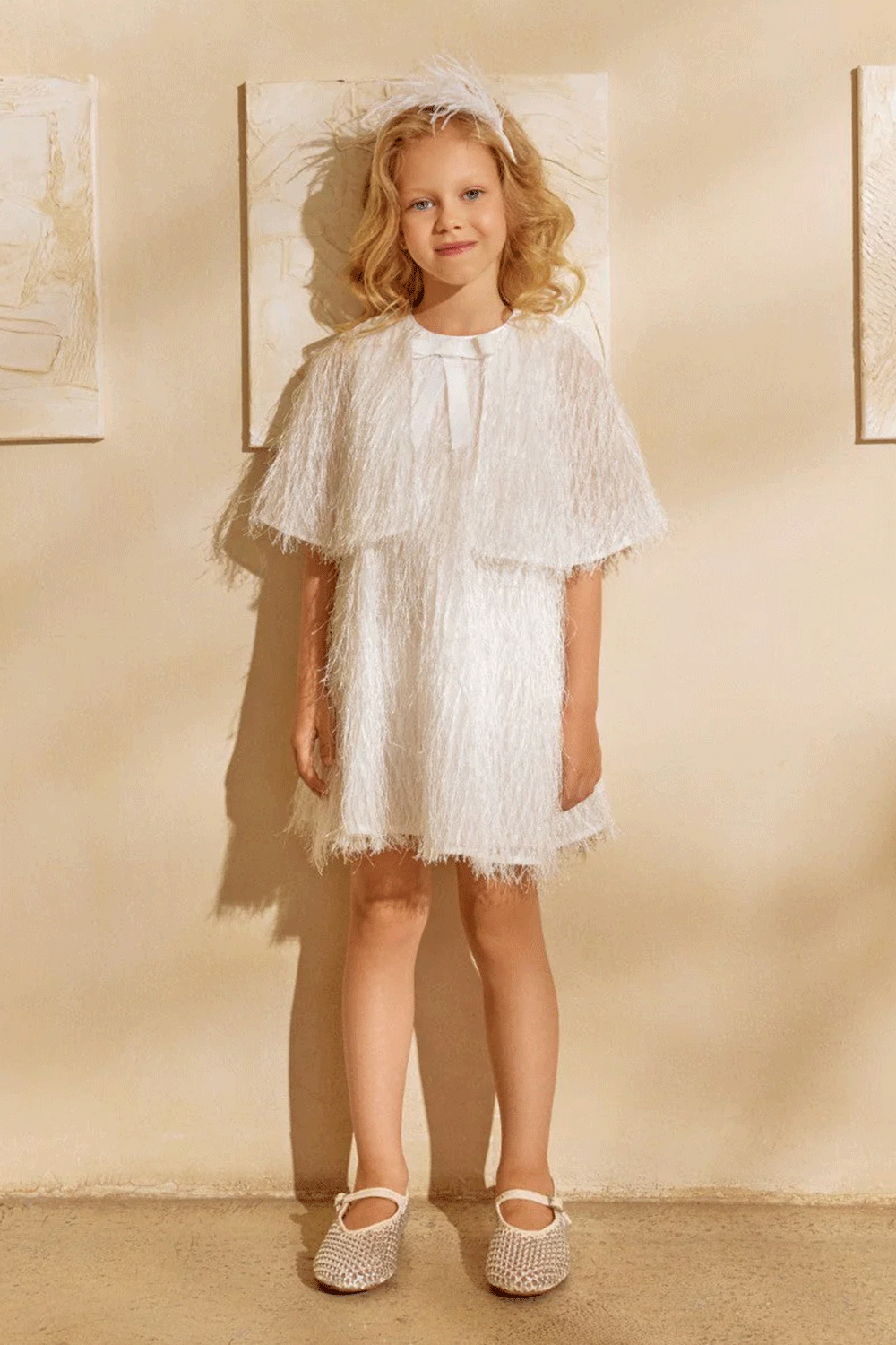 White dress with textured fringe shimmering fabric, featuring a cape-effect overlay and a bow detail