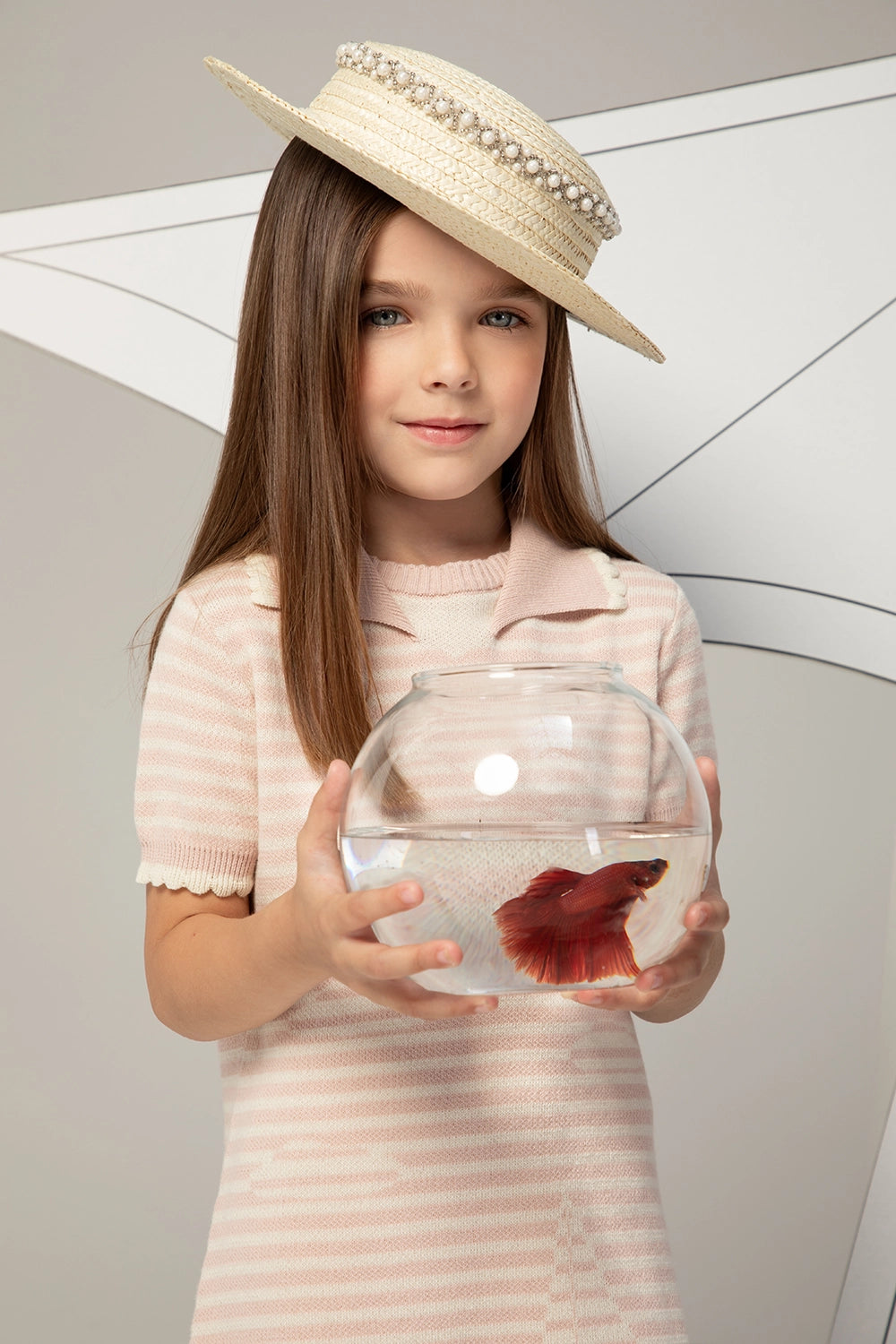 فستان محبوك مخطط باللونين الوردي الفاتح والأبيض بأكمام قصيرة وتفاصيل عند الياقة ونقشة قارب شراعي دقيقة.